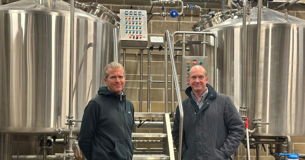 Aspall Cyder Brothers Aim for Beer Market Following Brewery Acquisition acquisition, alcohol, beer, brewery, Brothers, Cyder, Day, differential focus, easy retouch, England, Food and Drink, Here’s a list of comma-separated tags based on the title provided: Aspall, indoors, lake district, market, no people, pint glass, square image, table, Tradition, two objects Food and Beverage Business