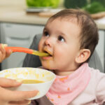 Kraft Heinz Unveils Significant Sale adult, Baby, baby boy, Baby food, beginnings, bowl, boy, Care, caucasian, child, childhood, color, cute, dependence, development, Eating, excitement, feeding, Female, food, green background, growth, hand, high chair, holding, horizontal, human arm, indoors, innocence, male, mother, mouth open, nutrition, Parent, parenthood, photography, sitting, sleeve, Son, spoon, studio shot, two people, unrecognizable person, Woman Food and Beverage Business